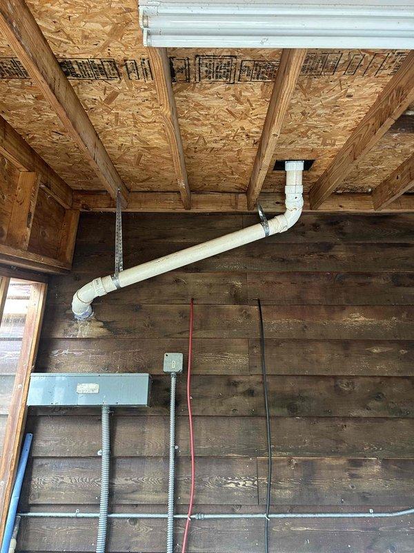 Completed roof vent repair associated with Trane HVAC system. Installed new black vent pipe with elbow configuration on proper flashing base, ensuring proper sealing to roof surface. Verified interior PVC drainage connections in utility area were secure and properly aligned with the exterior ventilation components.