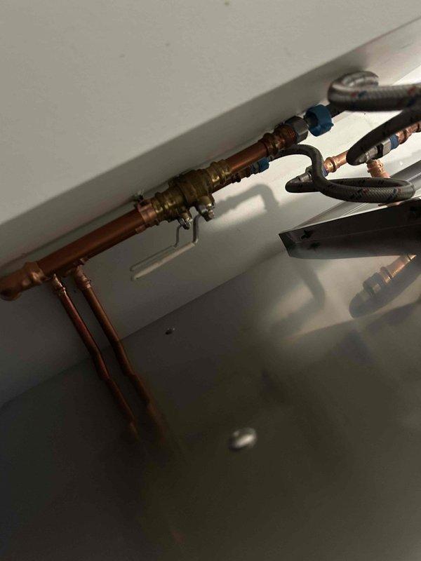 Relocated water supply valve to opposite side to conceal water lines as requested. Performed comprehensive 60-point plumbing system assessment and completed water heater flush service on tanked unit. Installation included proper copper pipe fitting with soldered joints and secure mounting hardware in the confined service area.