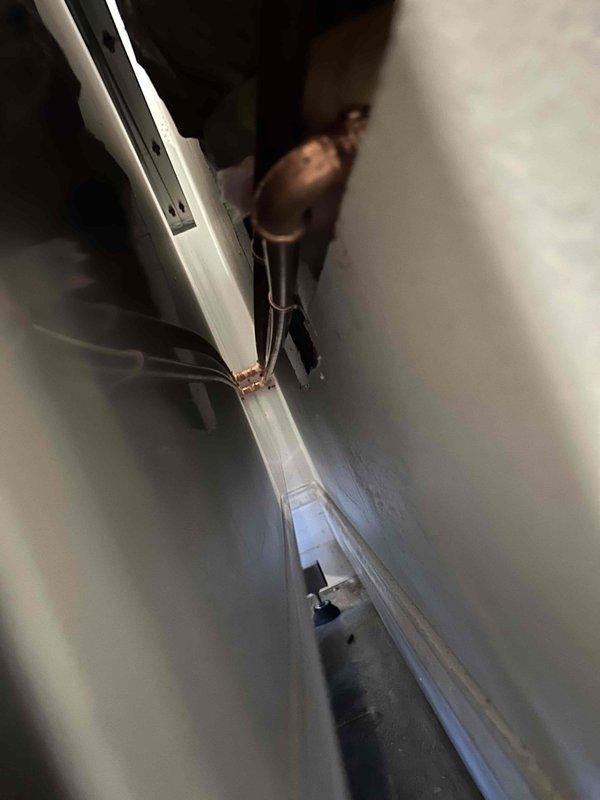 Relocated water supply valve to opposite side to conceal water lines as requested. Performed comprehensive 60-point plumbing system assessment and completed water heater flush service on tanked unit. Installation included proper copper pipe fitting with soldered joints and secure mounting hardware in the confined service area.