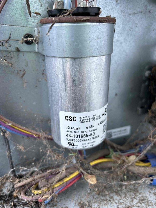 Diagnosed 5-year-old AC system that was blowing cold air. Multimeter testing revealed significantly low capacitance (27.17μF) on the dual run capacitor (30+5μF), which showed visible deterioration and dust accumulation. Replaced failing capacitor and cleaned debris from unit to restore proper cooling operation.