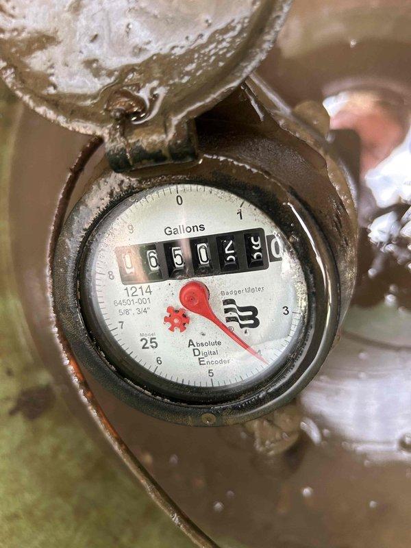 Responded to service call for reported water leak in a 70-year-old residence. Inspected water meter (BadgerMeter Model 25) which showed active consumption despite fixtures being off, confirming presence of a leak. Examination of the foundation perimeter revealed moisture accumulation near landscaping at the house exterior, indicating underground supply line damage requiring further excavation and repair.