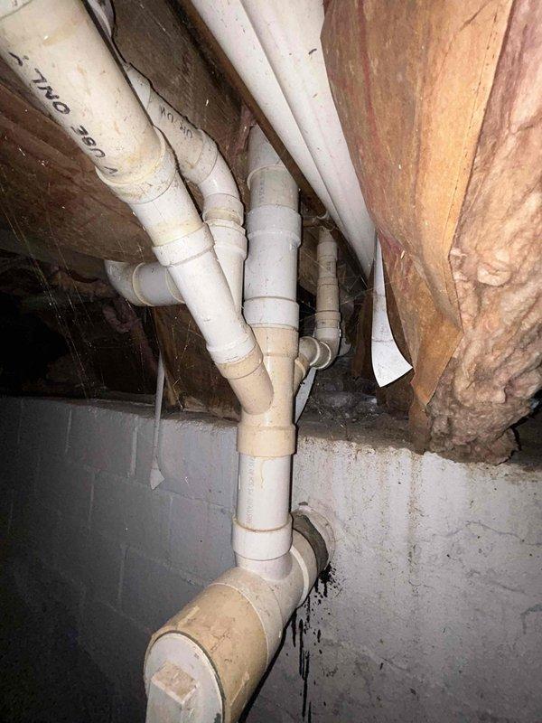 Conducted assessment of sump pump system requiring relocation from current position at front of residence adjacent to chain link fence. Inspection of crawlspace revealed existing PVC drainage network with multiple joints/connections mounted to wooden joists, with evidence of aging and possible moisture exposure. Quote prepared for complete sump pump relocation as requested.