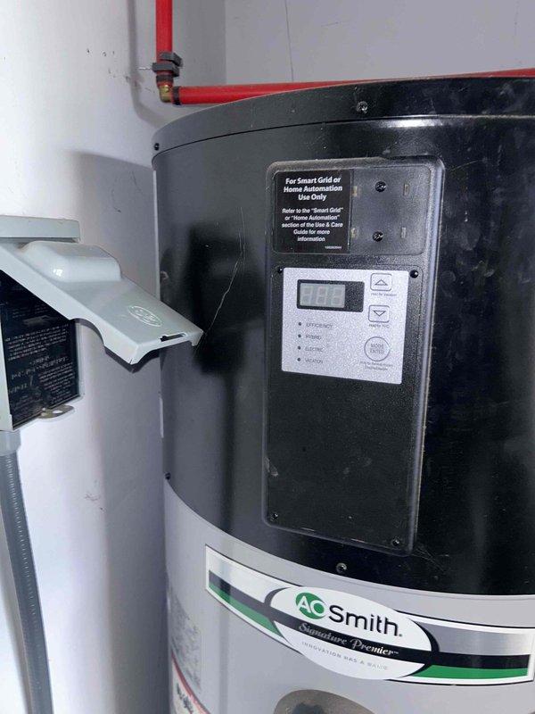 Performed standard maintenance flush on A.O. Smith Signature Premier tanked water heater to remove sediment buildup and maintain optimal performance. Inspected copper piping connections and verified proper operation of temperature controls, with digital display showing normal readings after service completion.