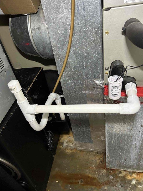 Responded to a no-cooling service call for an electric HVAC system under 10 years old. Discovered significant water damage and rust staining on the concrete floor beneath the air handler due to condensate drain line issues, with visible water leakage from the system. Identified that the filter was missing after previously being improperly secured with tape, potentially having fallen into the lower portion of the system, which was contributing to the operational failure and condensation problems.