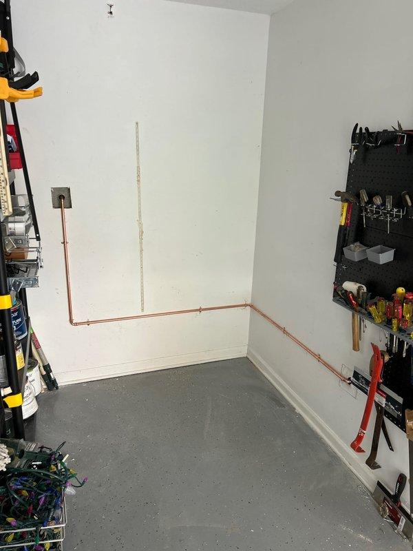 Cut in access panel in garage to install new copper supply line for exterior hose bibb. Replaced old fixture with new model and verified proper functionality of the outdoor faucet before completing job.
