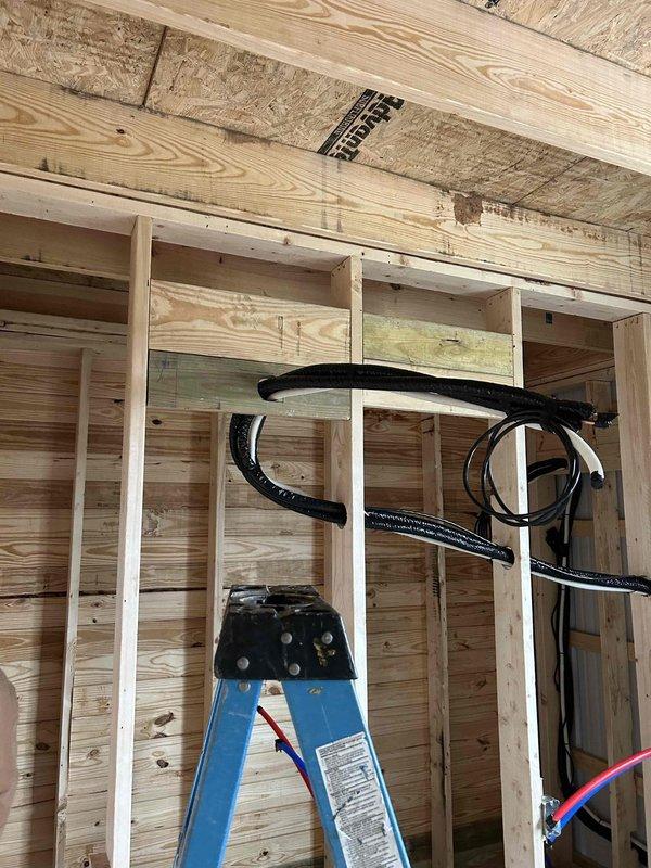 Successfully installed a Friedrich two-zone mini-split system consisting of a 27K BTU Low Temp Mini Split ProX Series outdoor unit with full capacity at 5 degrees, an 18K BTU indoor wall mount unit, and a 9K BTU indoor wall mount unit. Complete installation included line sets, outdoor unit pad, snow legs, electrical disconnect box, and refrigerant line insulation, with all components properly mounted and connected through the building's wooden framing structure.