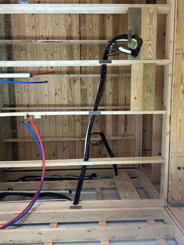 Successfully installed a Friedrich two-zone mini-split system consisting of a 27K BTU Low Temp Mini Split ProX Series outdoor unit with full capacity at 5 degrees, an 18K BTU indoor wall mount unit, and a 9K BTU indoor wall mount unit. Complete installation included line sets, outdoor unit pad, snow legs, electrical disconnect box, and refrigerant line insulation, with all components properly mounted and connected through the building's wooden framing structure.