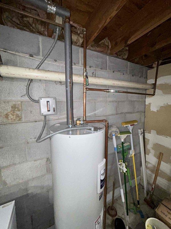 Completed installation of a 50-gallon electric tall water heater in basement utility area. Connected copper supply lines and properly vented the unit with appropriate metal vent pipe. Verified electrical connections to junction box with flexible conduit and ensured system was operational before completion.