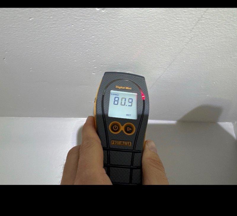 Conducted moisture inspection of interior wall junction following home inspection concerns. Moisture meter readings indicated significant water intrusion (80.9 with "WET" indication) in the ceiling-wall corner area. Documented evidence of potential plumbing leak requiring further investigation and repair to address inspector findings prior to property transfer.