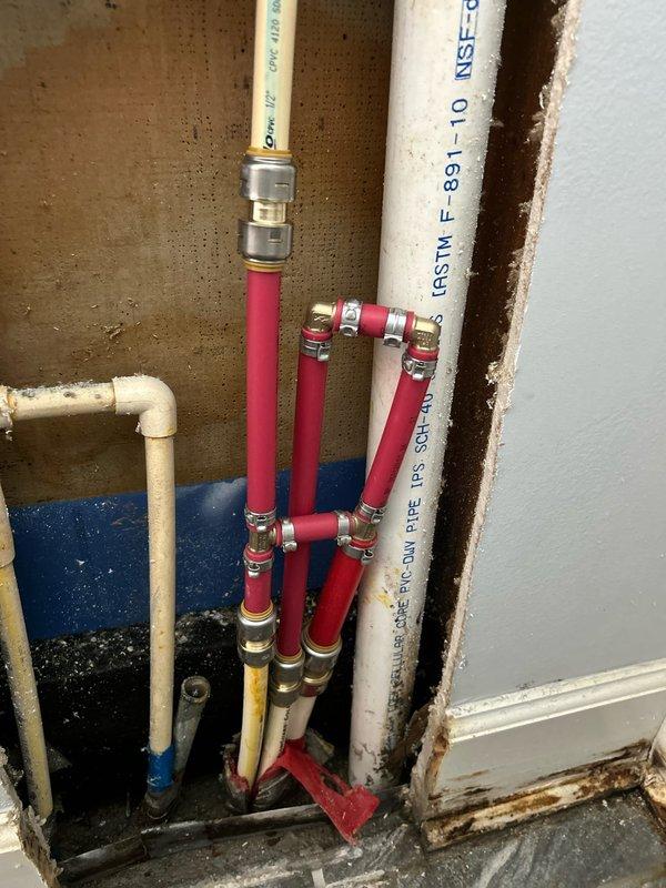 Responded to service call regarding water leak between shower and wall on concrete slab foundation. Upon inspection, removed drywall section to access plumbing components, revealing multiple PVC pipes with water supply lines and evidence of moisture damage. Identified leak source at PEX tubing connection points with metallic fittings, performed necessary repairs to resolve the water intrusion issue.
