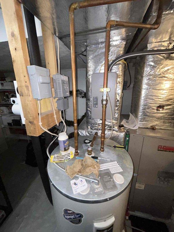 Conducted plumbing inspection of residential mechanical room, focusing on water heater system and associated copper piping. Changed batteries in the Resideo leak detector sensor as requested. Utilized extra-long snake to clear clogged drain. Tested bathroom sink water flow and drainage, confirming proper function after service.