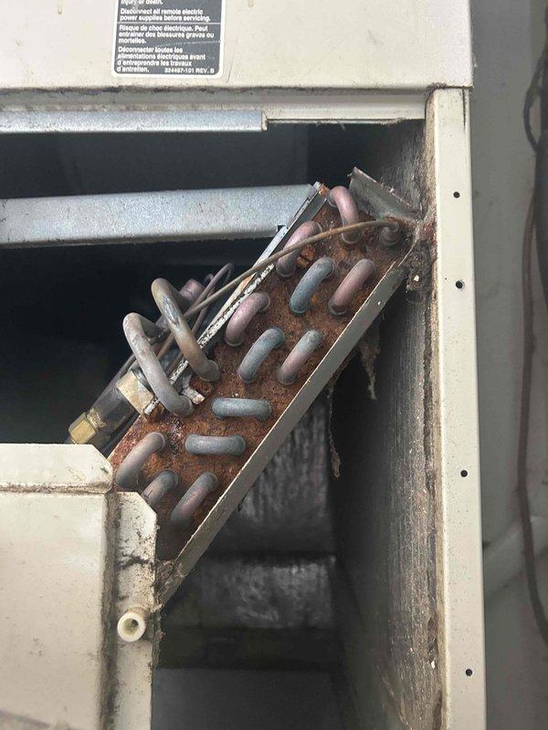 # Service Report

Responded to no cooling complaint on 2-year-old residential AC system. Upon inspection, discovered severely corroded electrical terminal block and connections at air handler, indicating significant moisture intrusion despite unit's young age. Corrosion had compromised electrical continuity, preventing system operation. Heat exchanger and evaporator coil showed heavy dust accumulation, restricting airflow and suggesting inadequate filtration. Documented extensive corrosion damage with photos showing rust-covered terminal assembly, deteriorated copper line connections, and compromised metal housing. Recommended immediate replacement of corroded electrical components and thorough system evaluation to identify moisture source before restoration of service.