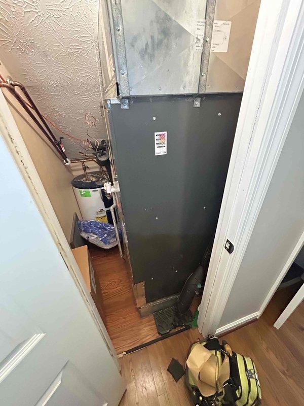 # HVAC Service Report - Musty Odor Complaint

Responded to service call for musty odor emanating from downstairs air conditioning system during cooling operation. Customer reported odor persisted even after extended runtime of 15-year-old AC system, which was still operational for cooling.

Upon arrival during requested evening service window, conducted visual inspection of HVAC equipment located in narrow utility closet. Accessed air handler unit and examined internal components for source of odor complaint. Inspection revealed significant rust corrosion and deterioration on evaporator coil drain pan assembly. 

Documented extensive orange-brown rust buildup along drain pan edges and channels, with yellowish-brown liquid residue pooled in bottom of corroded pan. Metal surfaces showed advanced oxidation and deterioration consistent with long-term moisture exposure. Condition of drain pan indicated chronic condensate management issues contributing to microbial growth and musty odor gene