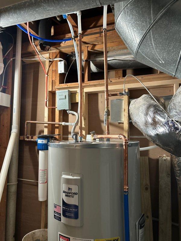 Completed installation of a new 50-gallon electric Bradford White water heater in an unfinished utility space. Positioned unit on concrete floor, connected copper supply and discharge lines with proper fittings, installed electrical conduit and wiring to power the unit, and integrated white PVC drain piping for temperature and pressure relief valve discharge. All connections were secured and tested to ensure proper operation and compliance with plumbing codes.
