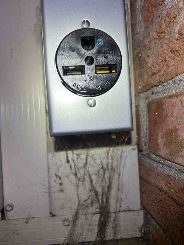 # HVAC Service Report - Mini Split No Power

Responded to service call for 12-year-old mini split system in sunroom with no power condition. Upon arrival, found unit completely non-operational with no response from controls. Inspection revealed compromised 250-volt dedicated outlet with evidence of significant electrical degradation, water intrusion damage, and heavy staining on surrounding surfaces beneath the receptacle. Outlet showed signs of long-term environmental exposure consistent with sunroom installation. Documented electrical connection points, terminal block configuration, and power supply components. Unit's age and electrical supply condition indicate need for further evaluation of power delivery system and potential component replacement to restore operation.