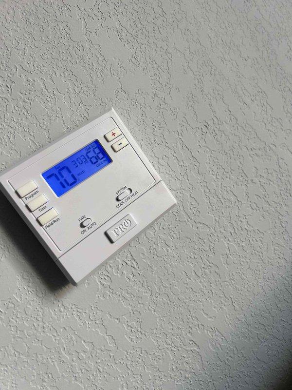 Responded to no cooling complaint on electric heat pump system. Upon arrival, thermostat displayed 70.5°F setpoint but system was not achieving temperature. Performed diagnostic inspection of indoor air handler unit located near entry door. Visually inspected electrical components including dual run capacitor and associated wiring connections. Examined capacitor terminals, control wiring (red, purple, yellow, blue, and orange conductors), and terminal block connections for signs of failure or degradation. Documented system conditions with photographs of thermostat display and internal electrical components for service records.