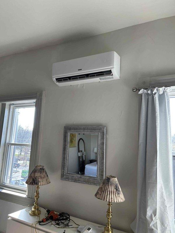 Completed residential installation of Durastar 18,000 BTU mini-split system consisting of model DRAW18F2A wall-mounted indoor unit and model DRA1U18S2A outdoor condensing unit. Indoor air handler was mounted on interior wall between two windows per specifications, while outdoor unit was positioned on concrete pad at ground level on rear exterior wall. Line set was secured vertically along exterior brick wall without line hide cover, with press fittings utilized for indoor unit connections in place of standard flares and Nyc-log sealant applied to outdoor unit flare threads. New dedicated electrical circuit was installed to power the system. System was pressure tested, evacuated, charged, and commissioned to manufacturer specifications. All equipment tested and verified operational upon completion.