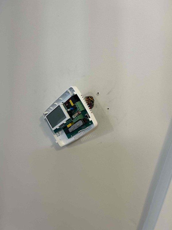 Responded to no heat call on older electric HVAC system located in second bedroom with reported breaker tripping issues. Upon arrival, performed diagnostic evaluation of thermostat and control system. Inspected wall-mounted thermostat unit, removed cover to access internal components and circuit board. Examined wiring connections, LCD display functionality, capacitor, relay, and terminal block connections for signs of electrical faults or component failure that could cause breaker trips. Documented internal condition of thermostat PCB and wiring configuration with photographs for service records.