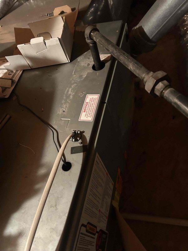 Responded to service call for thermostat with no power and non-functional HVAC system. Upon arrival, inspected 15-20 year old thermostat and traced wiring to furnace unit located in attic space. Verified power supply issues at equipment and assessed control panel connections. Documented existing system conditions including aged piping, control components, and overall unit configuration. Recommended thermostat replacement due to age and power delivery failure preventing heating and cooling operations.