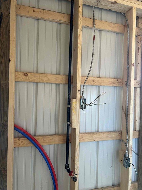 Installed complete gas piping system to supply two tankless water heaters in a residential or light commercial structure. Ran gas lines through interior wall framing with proper support and securing methods, installed exterior gas shutoff valve with yellow-handle ball valve on corrugated metal exterior wall, and ensured all connections meet code requirements for safe operation. All piping was properly sized and routed to accommodate dual tankless water heater installation.