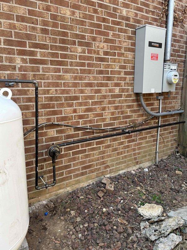 Completed gas piping installation for generator system, running LP gas line from propane tank regulator to generator connection point. Installed black gas piping with proper mounting hardware along exterior brick wall, ensuring secure attachment and code-compliant routing. Documented tile work repairs needed for property owner's contractor coordination.