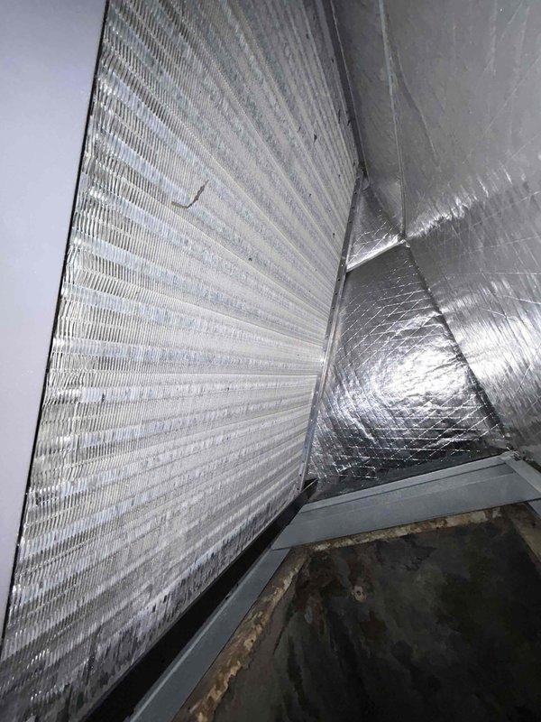 Completed comprehensive maintenance tune-up on heat pump and air handler system located in kitchen closet. Performed thorough inspection of all system components with particular attention to refrigerant levels as requested due to previous lineset repair history. Checked refrigerant charge and verified proper operation following earlier installation issues involving kinked lineset that required splicing and leak repair.

Inspected air handler unit and documented significant deterioration of drain pan showing heavy rust staining and accumulation of dirt, grime, and moisture residue. The condensate collection tray exhibited brown and orange discoloration around edges with dark contamination on interior surfaces, indicating need for future replacement consideration. Examined reflective insulation surrounding unit showing some white residue and staining.

Evaluated air filtration system with customer-provided 16x16x1 filter, noting dust and debris accumulation on pleated filter surface. Ins