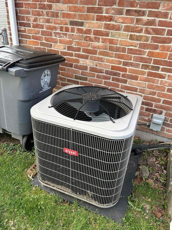 Completed comprehensive air conditioning tune-up and routine maintenance on a six-year-old residential AC system. Performed standard preventive maintenance procedures including inspection of outdoor condensing unit, verification of electrical connections at disconnect box, assessment of unit mounting and pad stability, and documentation of equipment condition. System found operating within normal parameters with no deficiencies noted. Unit exterior and surrounding area photographed for service records, showing proper installation on concrete pad against brick foundation with adequate clearance and access for future service.