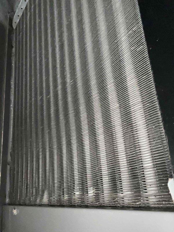 Completed scheduled care plan maintenance on upstairs air handler unit. Inspected evaporator coil assembly, noting accumulated dust and debris on fins with minor compression in several areas. Performed electrical diagnostics using clamp meter, recording amperage reading of 4.48 amps on system components. Documented equipment condition through photographs showing heat exchanger fins with oxidation and discoloration consistent with normal operation. All measurements within acceptable operating parameters for continued system performance.