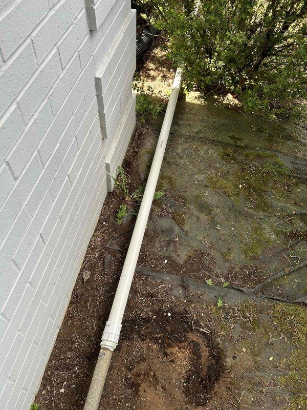 Successfully completed drainage system upgrade by connecting to existing galvanized discharge line and replacing with new 1.5-inch PVC pipe. Ran the upgraded discharge line past landscaping bushes to proper termination point in yard for improved drainage flow. All materials installed and system tested for proper operation.