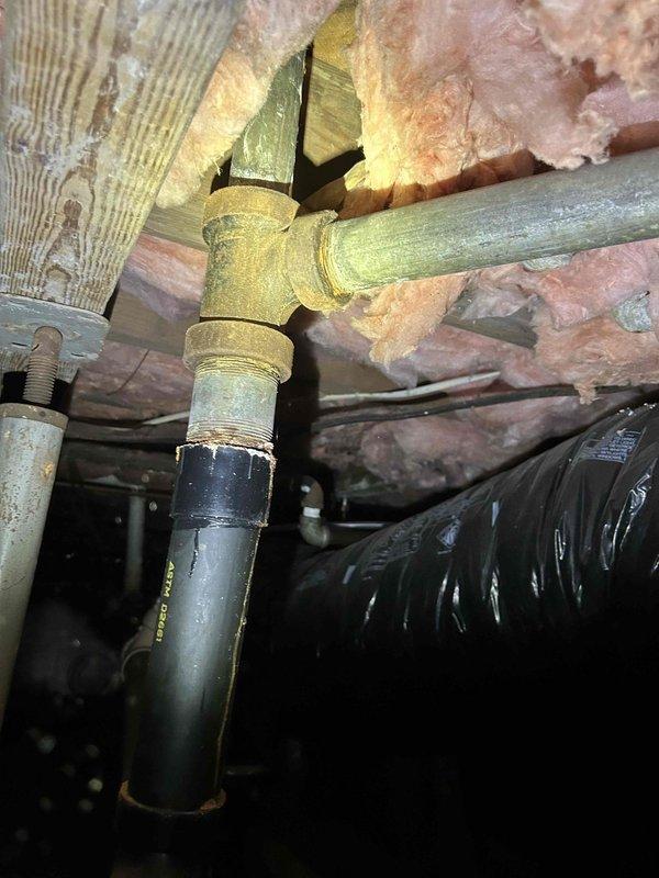 # Plumbing Estimate - Drain Line Replacement

Conducted comprehensive assessment of residential drain system requiring replacement of multiple fixtures and drain lines. Inspection revealed toilet drain line extending approximately 4 feet to main sewer connection required complete replacement due to deterioration or damage. Additionally, bathtub drain and overflow assembly needed replacement, along with the associated drain line running from tub to main sewer line.

Accessed crawl space and attic areas to evaluate existing plumbing infrastructure. Documented current conditions of cast iron and PVC drain piping, including T-joint connections and horizontal drain runs. Examined structural wooden joists and clearances for new pipe installation. Identified routing path for replacement drain lines through floor framing system while maintaining proper slope and code-compliant venting.

Assessment included evaluation of connection points at main sewer line, verification of pipe sizing requirem