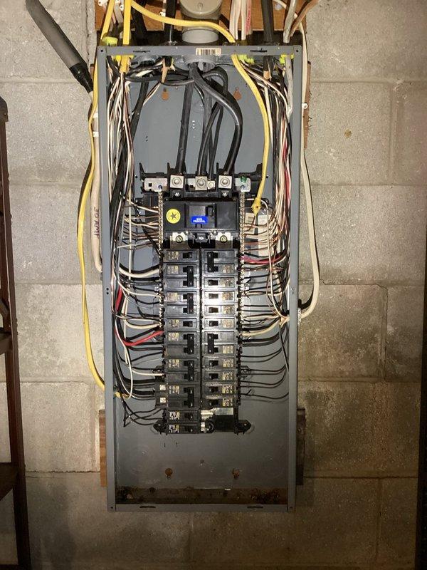 Conducted comprehensive electrical site assessment for backup generator installation at brick building. Evaluated existing electrical infrastructure including current meter location, service entrance configuration, and main distribution panel capacity. Documented exterior mounting locations for transfer switch and generator pad placement near existing HVAC equipment on gravel base. Assessed interior electrical panel with dual-row circuit breaker arrangement to determine integration requirements for automatic transfer switch installation. Photographed existing conduit routing and service entrance components to develop accurate material list and labor estimate for generator interconnection project.