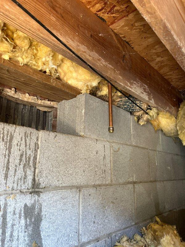 Responded to water leak originating from exterior hose bib penetrating into crawlspace. Upon inspection, identified leaking outdoor spigot mounted on brick exterior wall with compromised connections allowing water infiltration through wall penetration into crawlspace area. Observed moisture presence in crawlspace affecting floor joists, fiberglass insulation, and concrete block foundation wall. Repaired/replaced hose bib connections and fittings to eliminate active leak. Verified proper seal at wall penetration point to prevent future water intrusion into crawlspace. System tested and confirmed watertight operation upon completion.