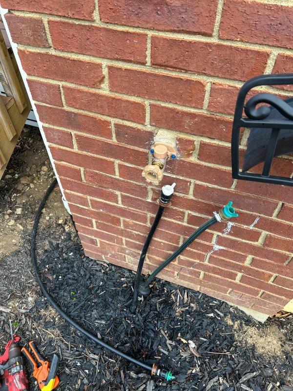 Responded to water leak originating from exterior hose bib penetrating into crawlspace. Upon inspection, identified leaking outdoor spigot mounted on brick exterior wall with compromised connections allowing water infiltration through wall penetration into crawlspace area. Observed moisture presence in crawlspace affecting floor joists, fiberglass insulation, and concrete block foundation wall. Repaired/replaced hose bib connections and fittings to eliminate active leak. Verified proper seal at wall penetration point to prevent future water intrusion into crawlspace. System tested and confirmed watertight operation upon completion.