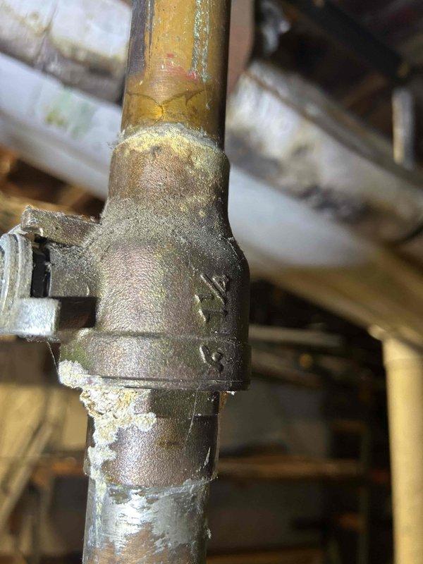 Responded to no-heat service call for boiler system that had been non-operational since property acquisition. Upon arrival, performed diagnostic inspection of boiler and associated piping infrastructure. Documented existing conditions including deteriorated pipe connections, corroded brass fittings with mineral deposits, and aging plumbing components showing significant wear. Assessed central cylindrical boiler component and surrounding pipe configuration with multiple joints and connections. Identified corrosion and discoloration on metal surfaces throughout the system. Photographed critical areas including compromised pipe unions and fittings requiring attention for proper system operation and safety compliance.
