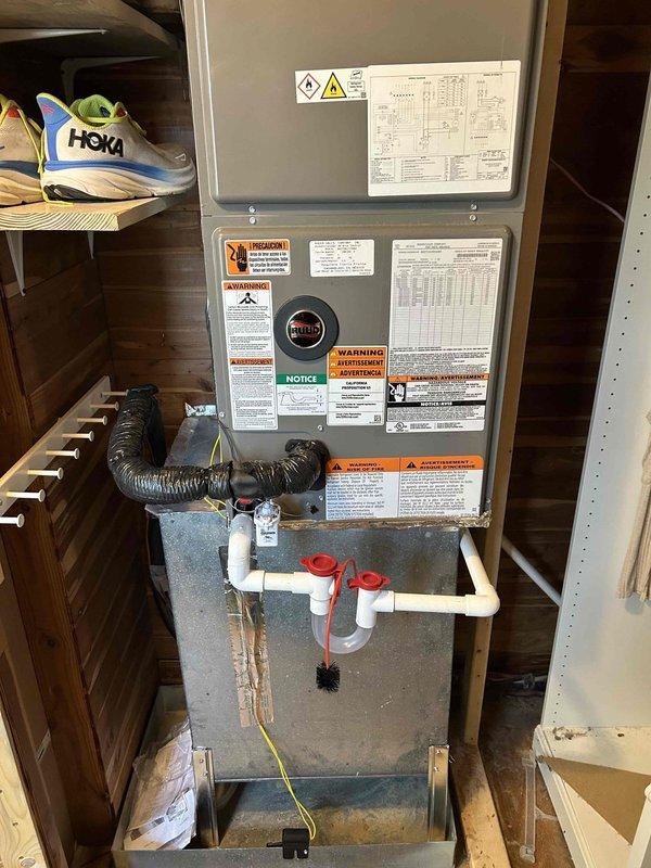 Completed full residential HVAC system installation including Ruud RP14AY30AJ2NA heat pump outdoor unit, RH2TY3617STANNJ air handler, and RXBH-1724A10J-B electric heat kit. Installed outdoor unit on new concrete pad with snow legs, electrical disconnect box, and electrical whip kit. Applied refrigerant line insulation and installed refrigerant line filter. Ran new high voltage wiring to air handler for electric heat strips. Installed air handler in utility closet with trap, SS2 coil drain safety water sensor, ceiling saver overflow drain pan with water sensor, and standard air filter rack. Fabricated transitions to connect to existing ductwork. Replaced condenser fan motor and installed new Honeywell S200 thermostat. Removed and disposed of existing equipment. Obtained applicable permits and ensured code compliance. System tested and verified operational with proper airflow, refrigerant charge, and electrical connections. Provided customer with warranty documentation covering one year 