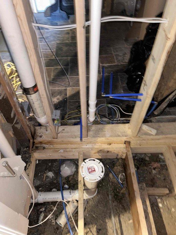 Completed rough-in plumbing work for bathroom renovation project. Installed white PVC drainage and supply lines through exposed floor joists and wall framing, including proper vertical pipe routing and water filtration system integration. Work included coordination with electrical infrastructure, ensuring all plumbing rough-in meets code requirements for future fixture set-out and finish work.