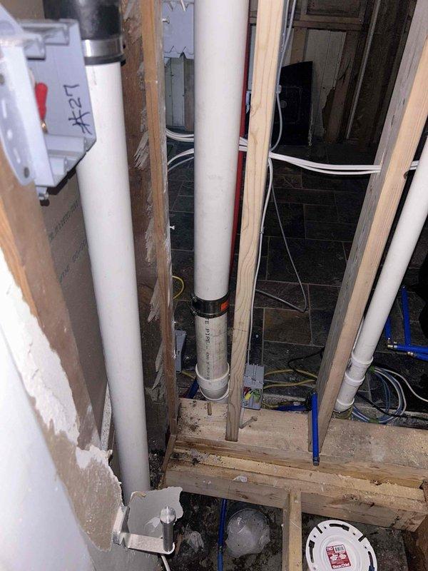 Completed rough-in plumbing work for bathroom renovation project. Installed white PVC drainage and supply lines through exposed floor joists and wall framing, including proper vertical pipe routing and water filtration system integration. Work included coordination with electrical infrastructure, ensuring all plumbing rough-in meets code requirements for future fixture set-out and finish work.