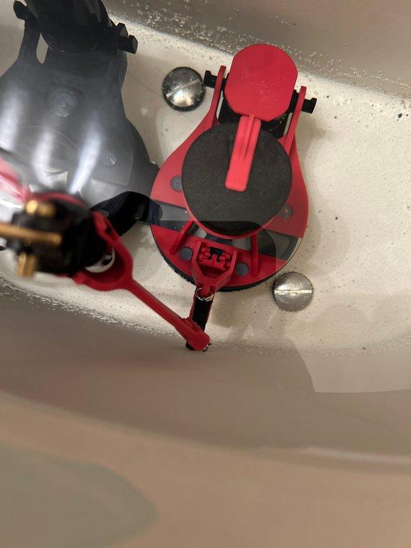 Responded to callback for recently installed toilet that was running continuously with intermittent bowl water loss. Upon inspection, identified faulty Fluidmaster fill valve assembly causing constant refill cycles. Removed defective red fill valve unit and replaced with new assembly, ensuring proper mounting and secure connections to water supply line. Adjusted float mechanism and verified proper shutoff operation. Tested system through multiple flush cycles to confirm bowl maintains proper water level and fill valve shuts off completely without continuous running.