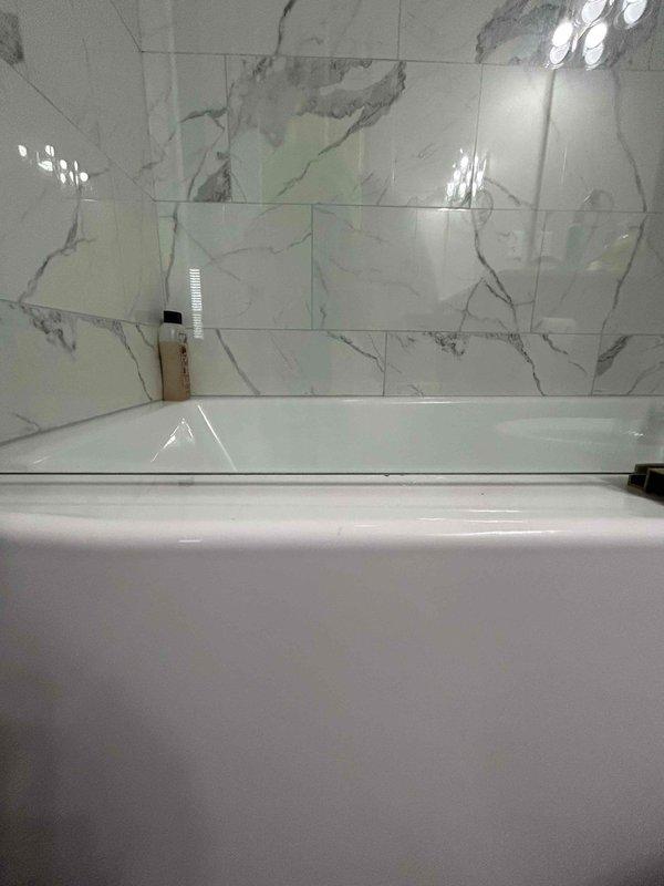 Responded to water leak investigation call at residential bathroom. Conducted thorough inspection of shower enclosure and bathtub area featuring marble-tiled walls and frameless glass panels. Located source of water intrusion and documented findings with photographic evidence. Identified leak origin point and explained repair requirements to customer for future remediation work.