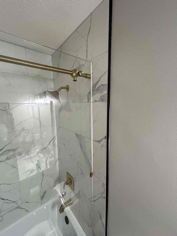 Responded to water leak investigation call at residential bathroom. Conducted thorough inspection of shower enclosure and bathtub area featuring marble-tiled walls and frameless glass panels. Located source of water intrusion and documented findings with photographic evidence. Identified leak origin point and explained repair requirements to customer for future remediation work.
