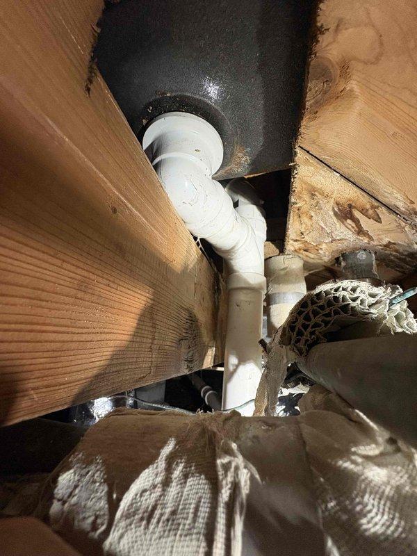 Responded to a recurring bathtub clog that had not been fully resolved by previous snaking attempts. Accessed the crawl space beneath the residence to inspect the drainage system and replaced deteriorated PVC piping sections. Installed new white PVC pipe assembly with proper joints, elbows, and secure metal strapping brackets to the floor joists to ensure proper drainage flow and prevent future blockages.