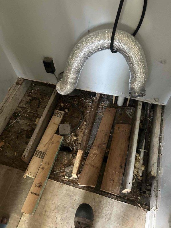 Responded to service call for kitchen remodeling project where removal of island platform exposed existing HVAC ductwork beneath floor. Upon arrival, inspected exposed floor cavity and identified flexible metallic supply duct running between floor joists along with PVC drain lines. Assessed ductwork condition and routing to determine if system was active and functional. Documented existing duct configuration with photographs showing duct suspended by straps in crawlspace area with accumulated debris present. Consulted with installer regarding original equipment layout and provided recommendations to customer on options for either removing non-functional ductwork or rerouting active supply lines to accommodate kitchen renovation plans.