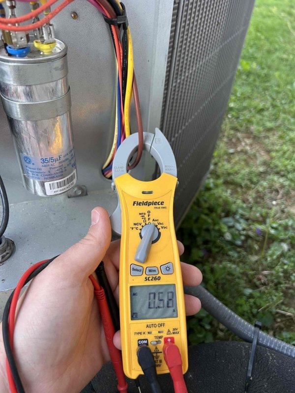 Performed routine maintenance on 2024 heat pump system with attic-mounted air handler. Conducted electrical diagnostics on outdoor condensing unit using clamp meter, verifying amperage draw at 0.56 amps, and inspected dual-run capacitor rated at 35/5µF for proper operation. Confirmed thermostat functionality showing system maintaining 70°F indoor temperature with 27% humidity and verified heating and cooling setpoints programmed correctly.