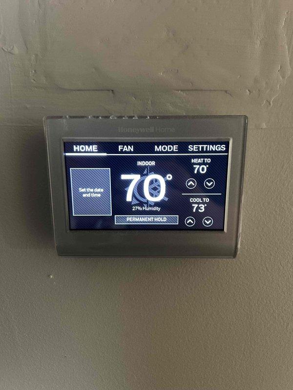 Performed routine maintenance on 2024 heat pump system with attic-mounted air handler. Conducted electrical diagnostics on outdoor condensing unit using clamp meter, verifying amperage draw at 0.56 amps, and inspected dual-run capacitor rated at 35/5µF for proper operation. Confirmed thermostat functionality showing system maintaining 70°F indoor temperature with 27% humidity and verified heating and cooling setpoints programmed correctly.