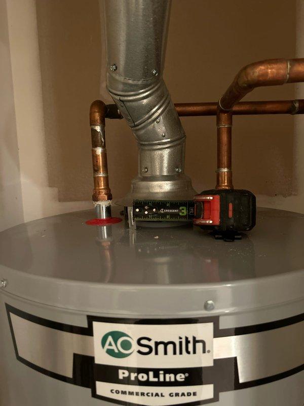 Responded to service call for assessment of water heater venting system flagged by inspector as undersized for the installed unit. Upon arrival, inspected A.O. Smith ProLine Commercial Grade tanked water heater located in second-floor utility closet, approximately one year old and in otherwise good operating condition.

Conducted thorough evaluation of existing venting configuration, including measurement and documentation of current vent pipe diameter and routing. Utilized digital level to verify proper pitch and alignment of exhaust vent system. Examined the galvanized metal flue pipe extending from top of unit, including elbow joint and connection points secured with metal bands. Assessed clearances, combustion air supply, and overall installation compliance with manufacturer specifications and current building codes.

Confirmed inspector's findings that existing vent pipe diameter does not meet required specifications for this commercial-grade water heater model. Documented install