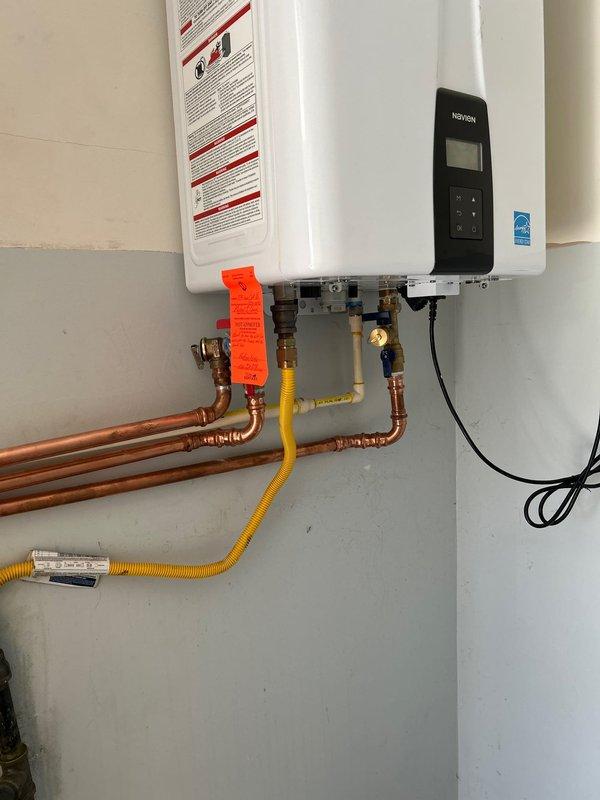 Addressed failed inspection items on gas tankless water heater installation. Rerouted temperature and pressure relief valve discharge line to exterior using proper CPVC piping per code requirements. Relocated condensate drain line to terminate outside the building, replacing non-compliant PE tubing with code-approved CPVC material where stubbed through exterior wall.
