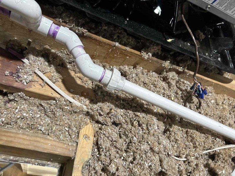 Responded to attic HVAC system experiencing drainage issues. Repaired and reconfigured condensate drain line with new PVC piping and fittings to ensure proper water evacuation from the unit. Installed drain pan beneath the equipment staging area to capture any overflow and prevent water damage to the wooden platform and surrounding structure. Verified proper drainage flow and secured all plumbing connections to prevent future leaks.