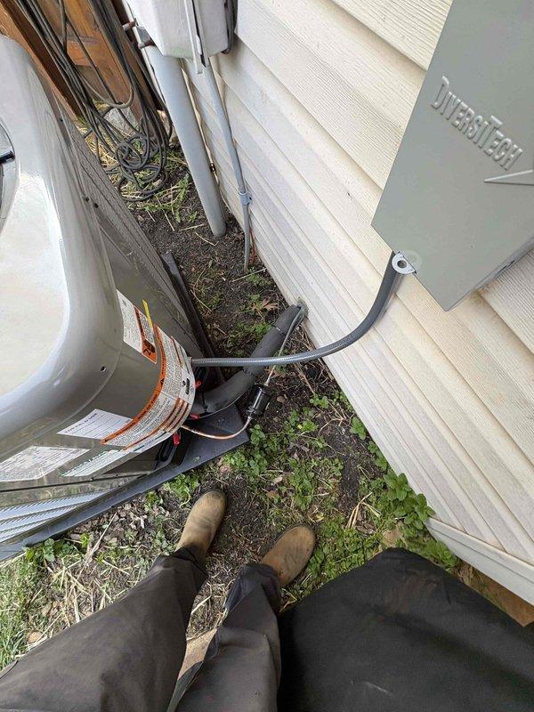 Completed full residential HVAC system installation featuring a RUUD 14.3 SEER2 2.5-ton two-stage heat pump (model RP14AY30AJ2NA), RUUD air handler (model RH2TY3617STANNJ), and RUUD 15KW heat kit (model RXBH-1724A15J-B). Installed Honeywell digital WiFi thermostat for remote system control and monitoring. Modified return air system by installing 16-inch metal elbow and 20x25 return filter grille to ensure proper airflow for optimal system performance.

Outdoor unit installation included placement on equipment pad with snow legs for elevation and drainage, electrical whip kit for flexible connection, and electrical disconnect box with interlock safety feature mounted to building exterior. Refrigerant lines were insulated and properly secured between outdoor condenser and indoor air handler. System was charged with 14.75 pounds of refrigerant as verified by digital scale measurement.

Indoor air handler installation incorporated SS2 coil drain safety water sensor, "Ceiling Saver" overflo