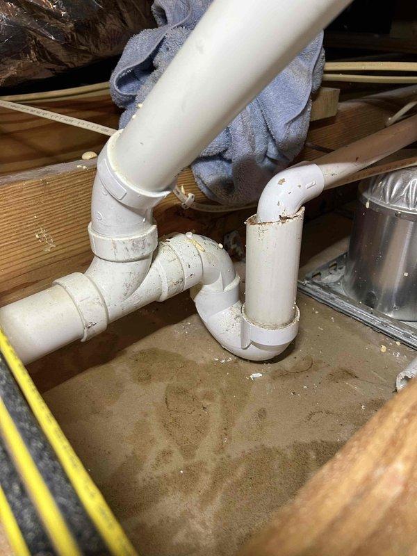 Responded to water leak complaint with indoor unit located in attic space. Upon inspection, identified active condensate drainage issue causing water to drip through ceiling fixture below. Examined PVC condensate drain line configuration and P-trap assembly in attic, finding debris accumulation and improper drainage flow. Cleared blockage from drain line, verified proper trap operation, and confirmed condensate flow restoration. Tested system operation and verified no further leakage present.