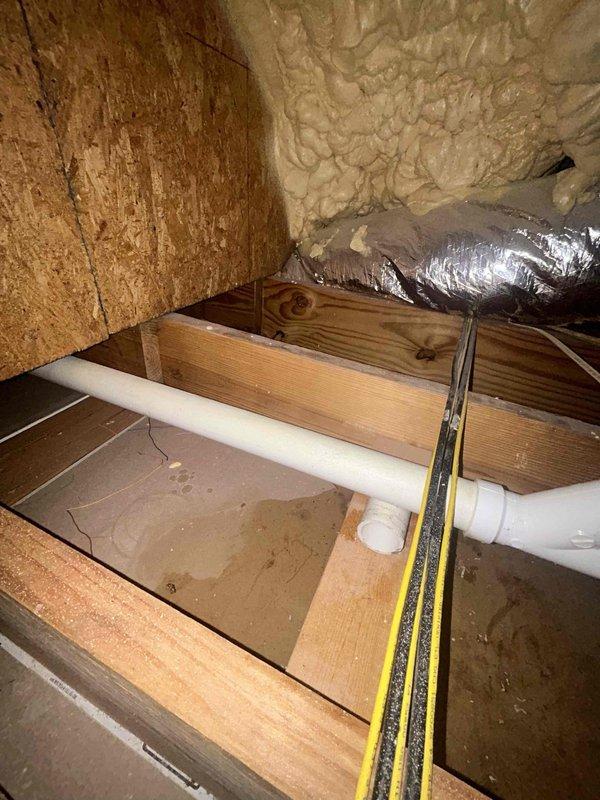 # Attic Drain Line Repair

Responded to clogged drain issue in attic crawl space. Upon inspection, identified defective tee fitting in main drain line causing blockage and potential backup. Accessed confined attic space through existing entry point and navigated around HVAC ductwork and insulation to reach affected plumbing system.

Removed damaged PVC tee fitting and surrounding compromised pipe sections. Cleared debris and buildup from drain line to ensure proper flow. Installed new PVC tee fitting with appropriate elbow connections, ensuring proper pitch and alignment for optimal drainage. Secured all joints with primer and PVC cement per code requirements. Tested system for leaks and verified proper water flow through repaired section.

Confirmed no moisture damage to surrounding wooden structural members or insulation. Restored work area and removed all debris. System operational and draining properly upon completion.